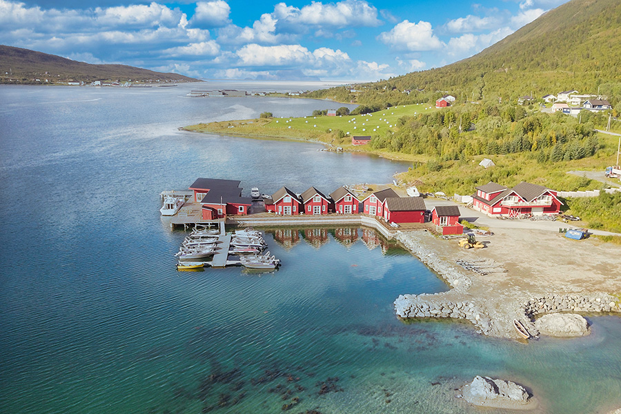 Traumhaft vor einer imposanten Bergkulisse gelegen: die roten Rorbuer des Lyngen Havfiske & Tursenters.